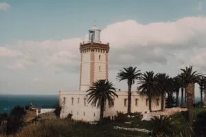 Historic lighthouse standing on the rugged coastline of Tangier, Morocco, overlooking the meeting point of the Atlantic Ocean and the Mediterranean Sea, with dramatic rocky cliffs and deep blue waters stretching to the horizon.