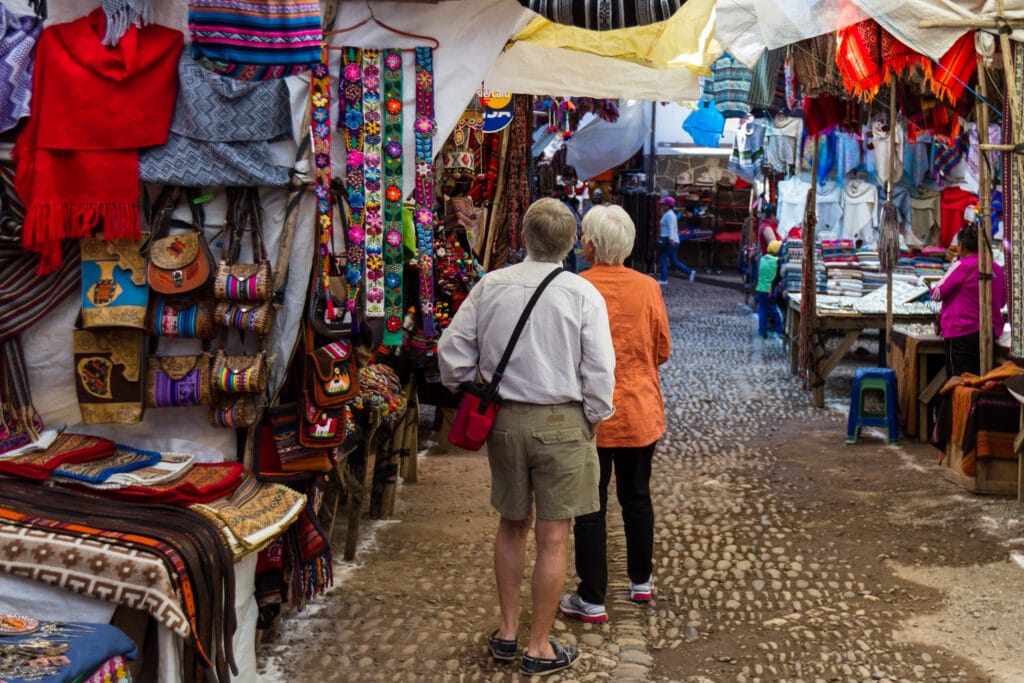 Travelers exploring a traditional market street in the Medina of Marrakech, Morocco